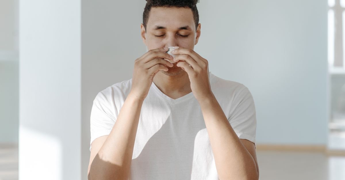 Homem leva um lenço de papel ao nariz