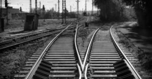 Trilhos de ferrovia se cruzam em um entroncamento ferroviário, em imagem em preto e branco