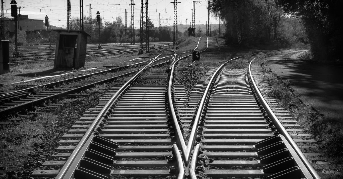 Trilhos de ferrovia se cruzam em um entroncamento ferroviário, em imagem em preto e branco
