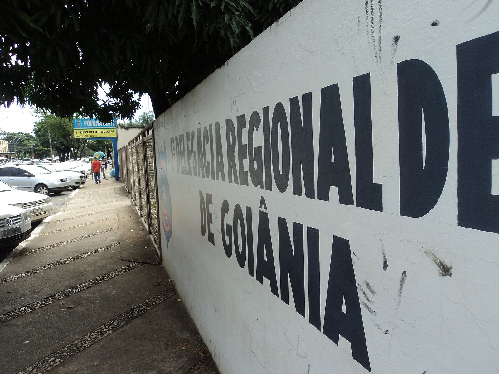 Fachada de delegacia da Polícia Civil de Goiás, com muro branco e letreiro em letras pretas