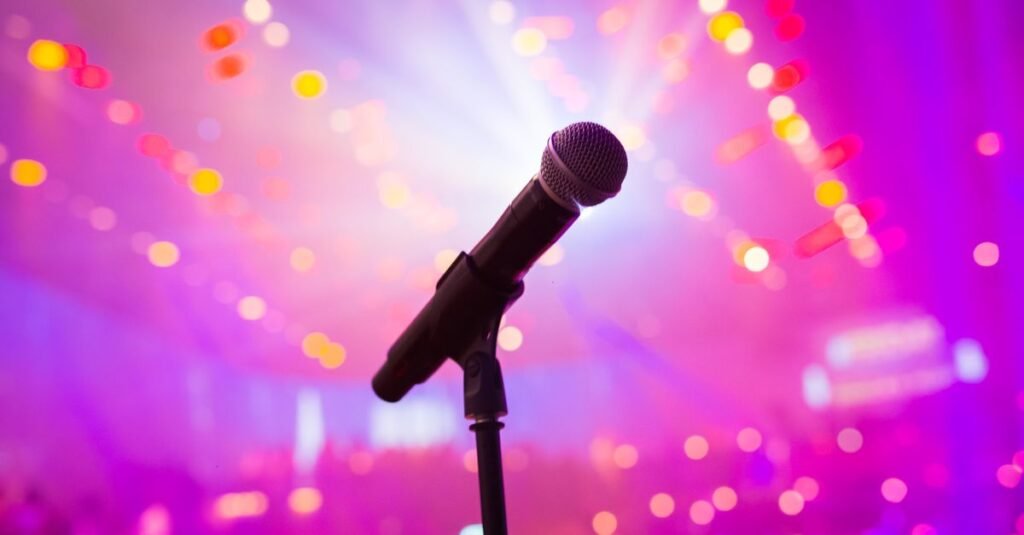 Microfone em pedestal no palco iluminado por luzes coloridas