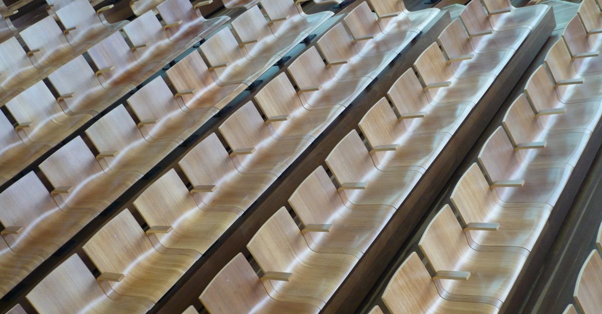 Fileiras de assentos de madeira em auditório vazio