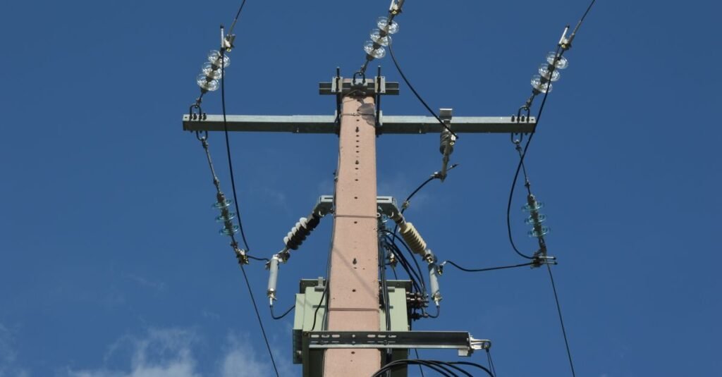 Poste de distribuição de energia elétrica com isoladores e cabos contra o céu azul