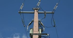 Poste de distribuição de energia elétrica com isoladores e cabos contra o céu azul