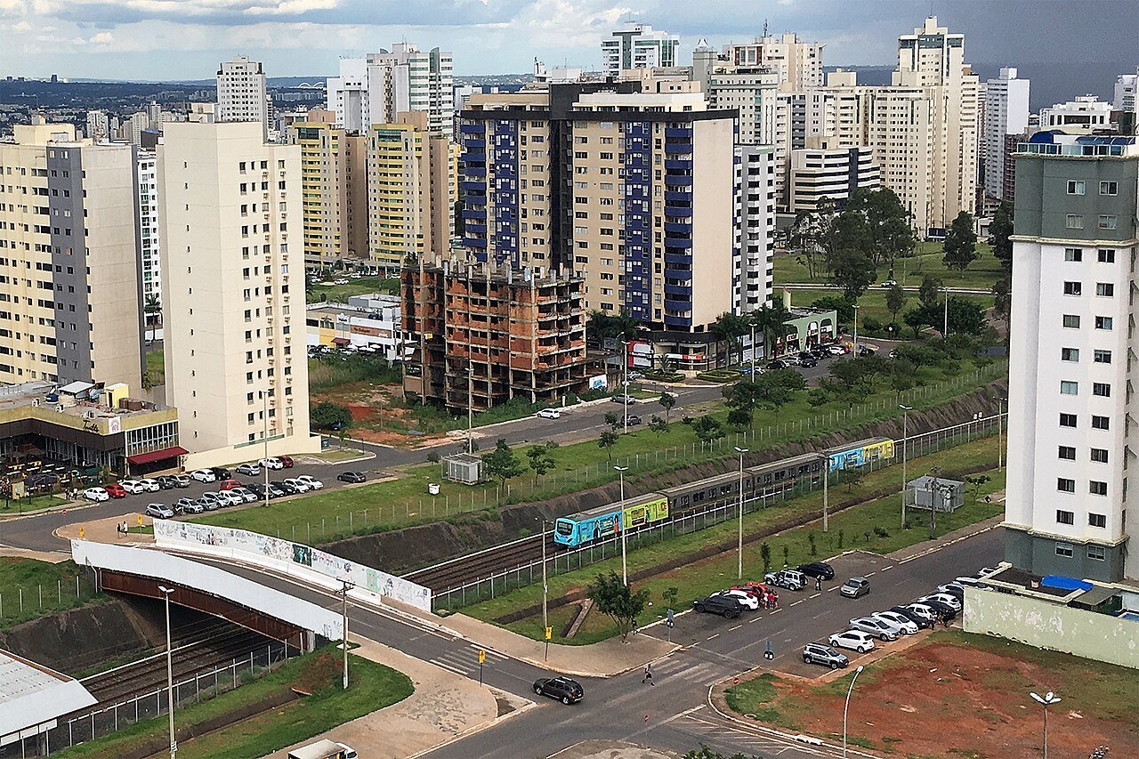 Trem do Metrô do Distrito Federal em trecho de superfície da linha, em Águas Claras, com prédios residenciais ao fundo