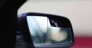 Retrovisor lateral de carro com o espelho quebrado e trincado em primeiro plano