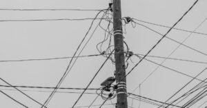 Poste de madeira com emaranhado de fios elétricos contra o céu cinza