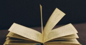 Livro antigo aberto com as páginas em meio a um movimento de virada