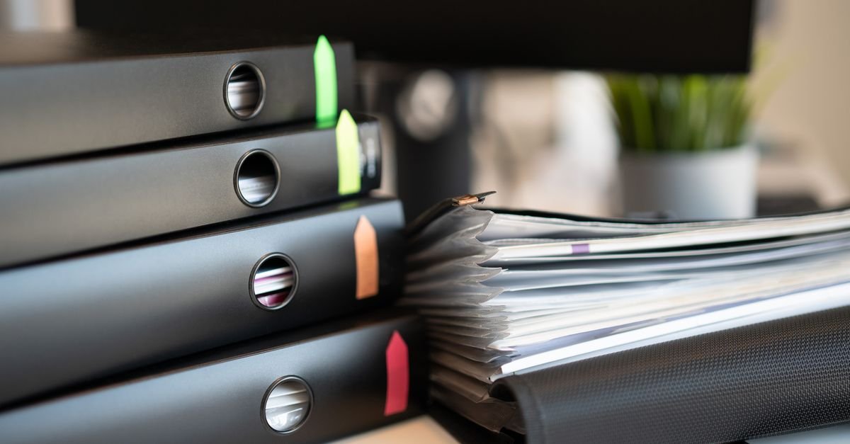 Pastas de processos empilhadas sobre mesa de escritório
