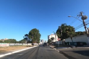 Rua comercial de Vicente Pires com carros estacionados e postes