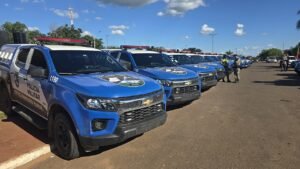 Viaturas da Polícia Militar de Goiás enfileiradas em pátio, com policiais ao fundo