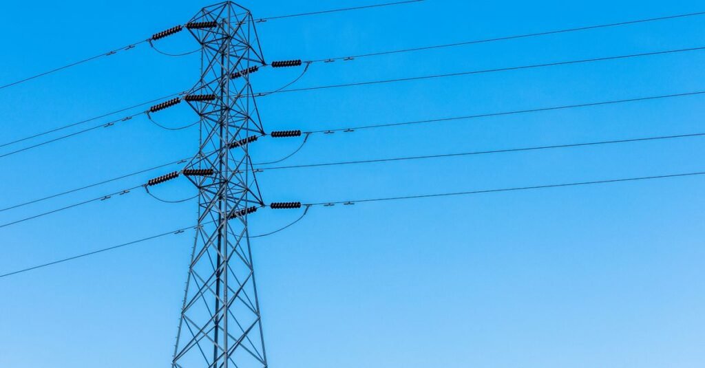 Torre de transmissão de energia elétrica com cabos sob céu azul