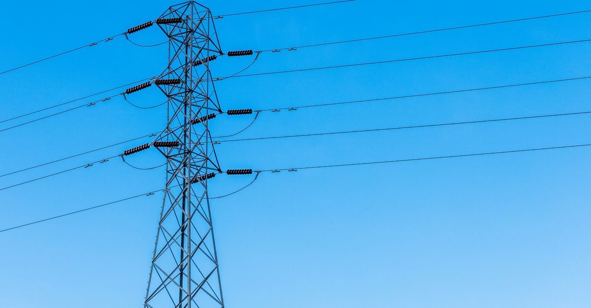 Torre de transmissão de energia elétrica com cabos sob céu azul