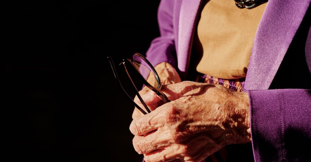 Maos de pessoa idosa segurando oculos
