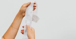 Mãos segurando um cupom fiscal de papel longo contra fundo claro