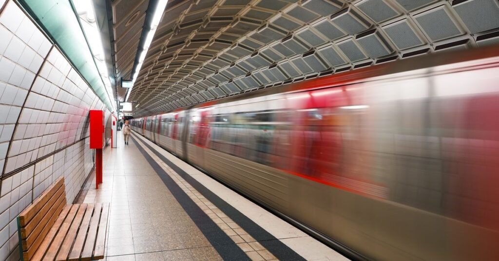 Trem de metrô em movimento chegando à plataforma de uma estação