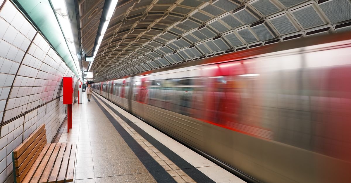 Trem de metrô em movimento chegando à plataforma de uma estação