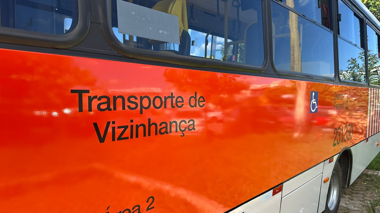 Lateral de ônibus zebrinha laranja do Distrito Federal com a inscrição Transporte de Vizinhança e o símbolo de acessibilidade