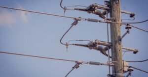 Poste de energia elétrica com fiação e isoladores contra o céu azul