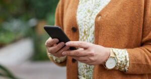 Mãos de pessoa idosa segurando um telefone celular