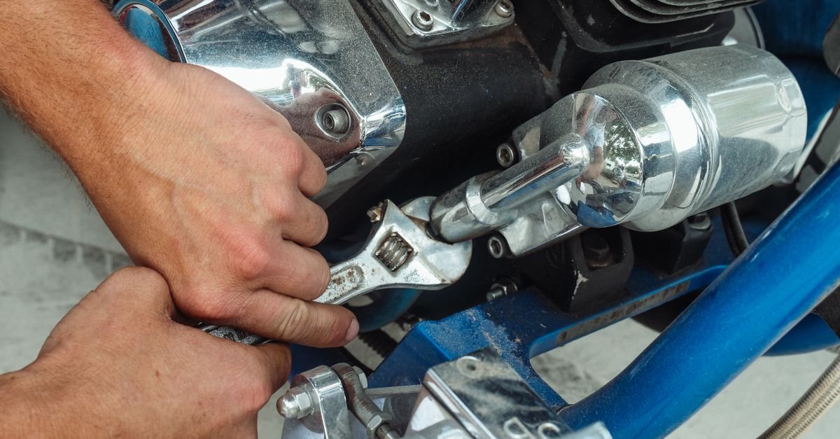 Maos de mecanico usando chave inglesa em motor de motocicleta