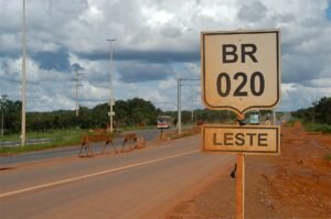 Trecho da BR-020 em Planaltina, com solo vermelho e vegetação de cerrado às margens da pista