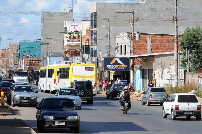 Via comercial movimentada do Itapoã, no Distrito Federal, com ônibus, carros e lojas