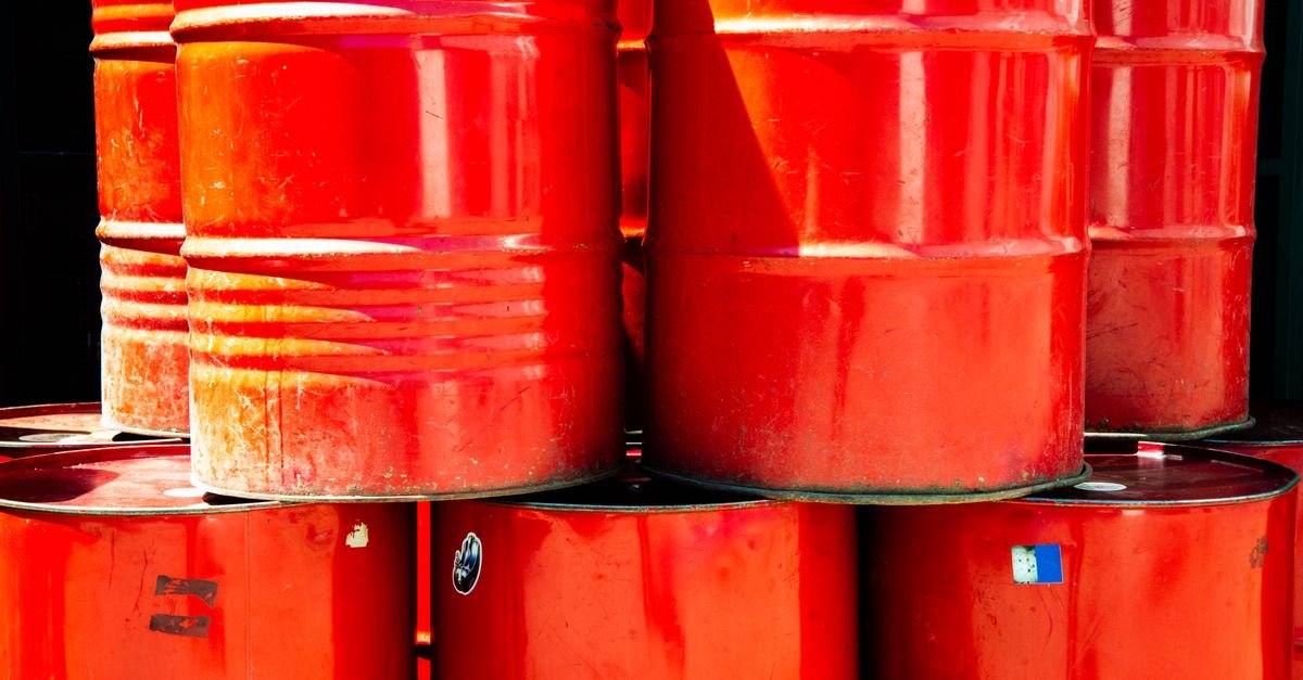 Tambores metálicos vermelhos de óleo empilhados em área industrial