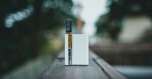 Cigarro eletrônico com refil de líquido apoiado sobre uma superfície de madeira ao ar livre
