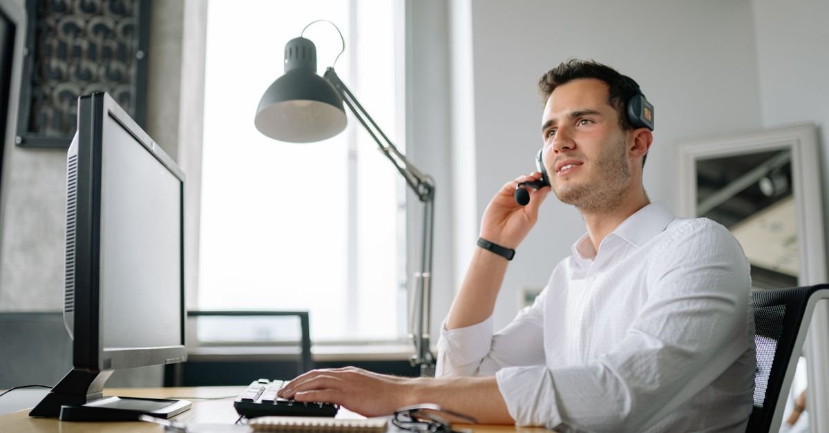 Atendente de central de relacionamento com fone de ouvido diante do computador