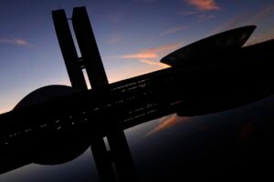 Silhueta do Congresso Nacional ao anoitecer, com as duas torres e as cúpulas refletidas no espelho d'água