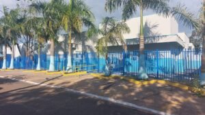 Fachada de Unidade Básica de Saúde com grade azul e palmeiras