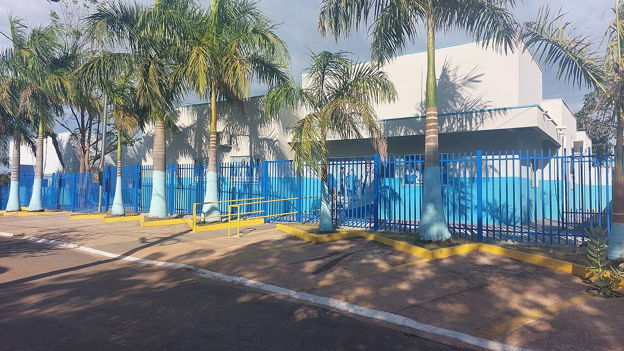 Fachada de Unidade Básica de Saúde com grade azul e palmeiras
