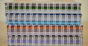 Pilha de cadernos coloridos sobre mesa, ilustrando o financiamento estudantil