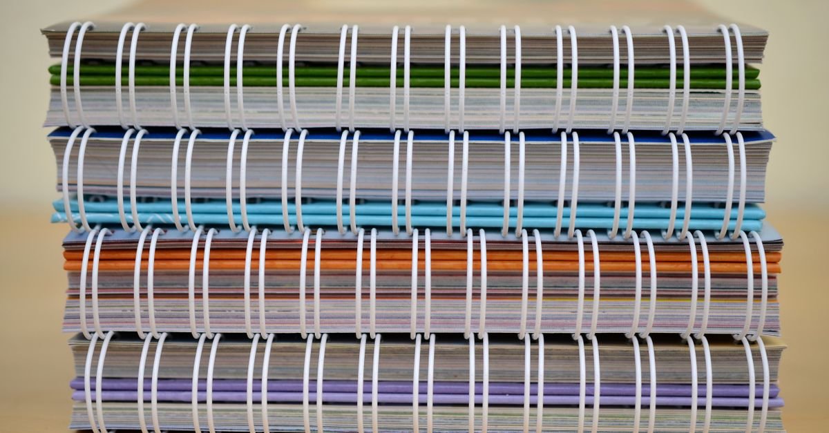 Pilha de cadernos coloridos sobre mesa, ilustrando o financiamento estudantil