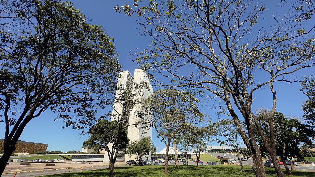 Torre do edifício principal do Congresso Nacional, em Brasília, vista entre árvores
