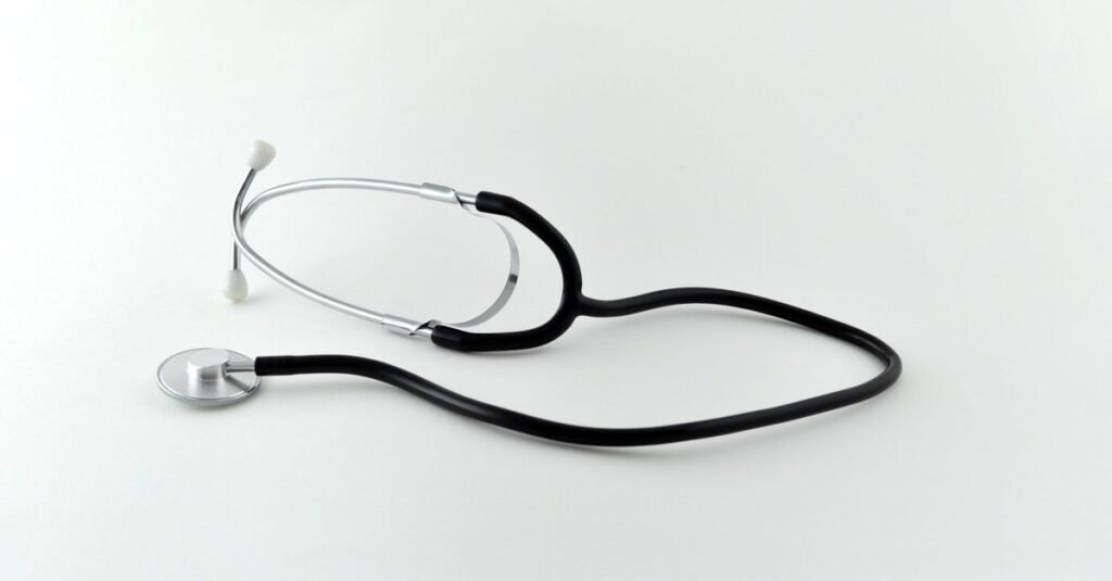 Estetoscópio preto sobre superfície branca, em imagem que ilustra assistência médica
