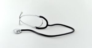 Estetoscópio preto sobre superfície branca, em imagem que ilustra assistência médica