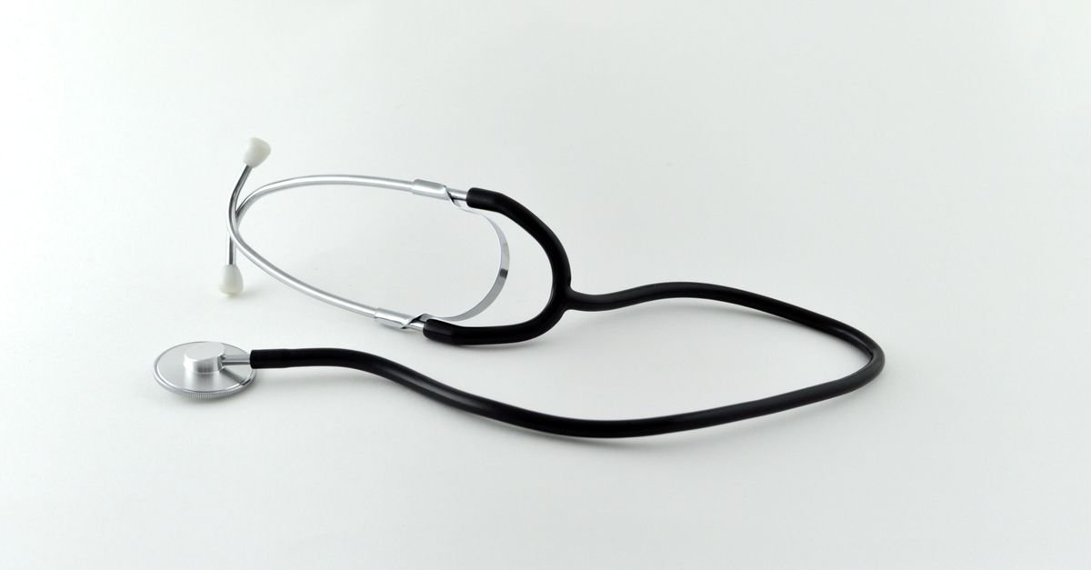 Estetoscópio preto sobre superfície branca, em imagem que ilustra assistência médica