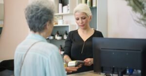 Cliente paga com cartão em maquininha no caixa de um salão de beleza
