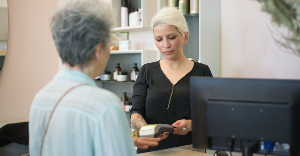 Cliente paga com cartão em maquininha no caixa de um salão de beleza