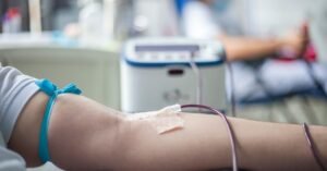 Braço de doador com garrote e agulha durante coleta de sangue