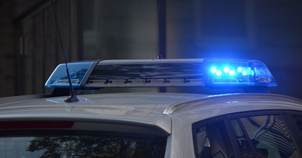 Barra de luzes azuis acesa no teto de uma viatura policial à noite