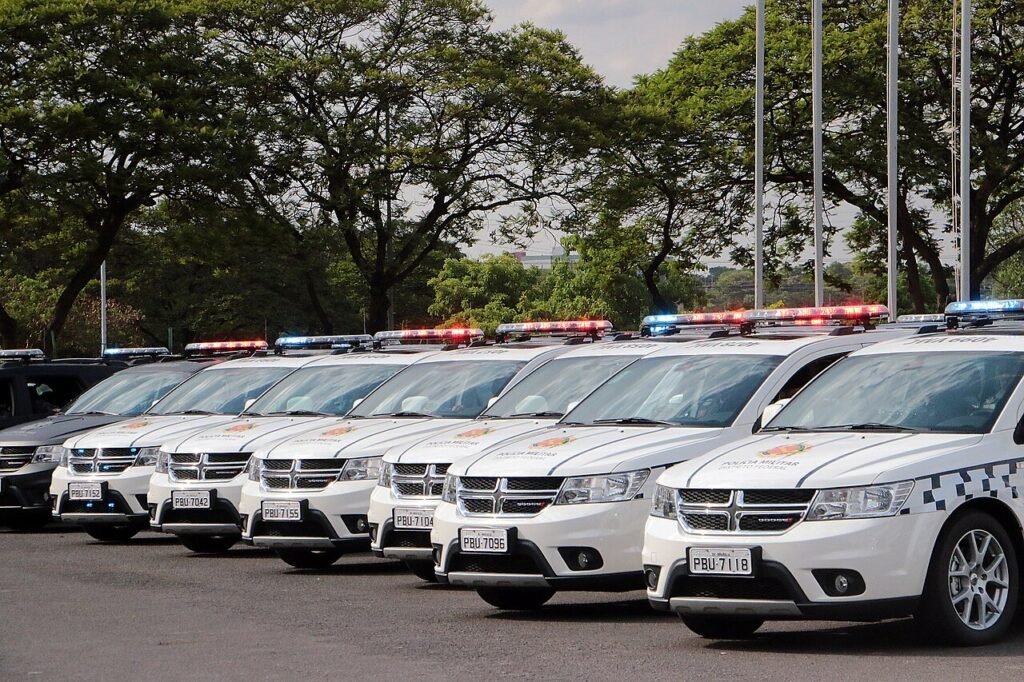Fileira de viaturas brancas da Polícia Militar do Distrito Federal estacionadas, com giroflex ligado