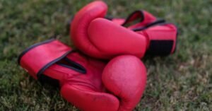 Par de luvas de boxe vermelhas apoiadas sobre a grama