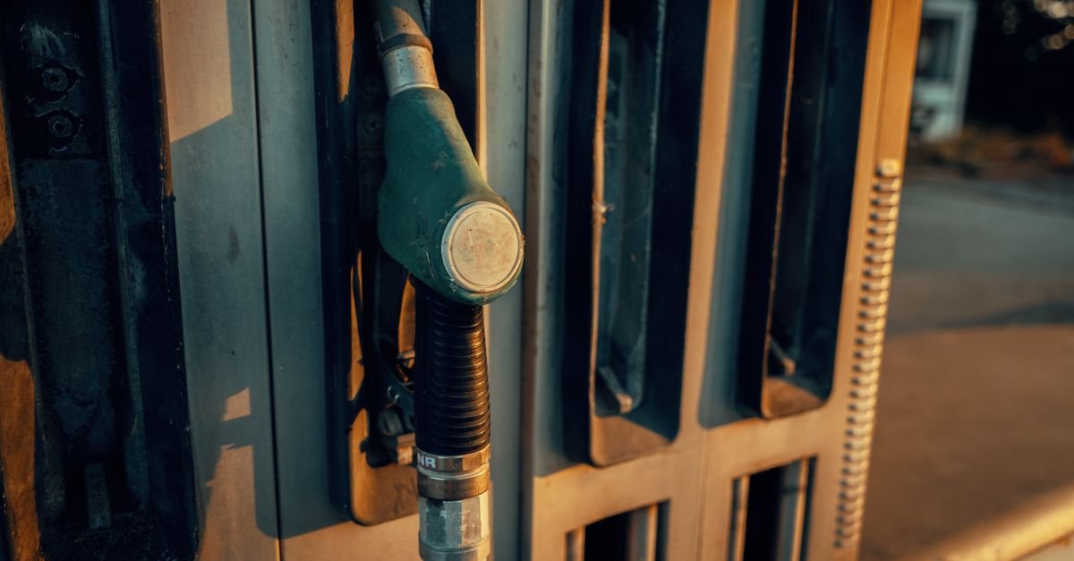 Bico de bomba de combustível encaixado na bomba de um posto, em close