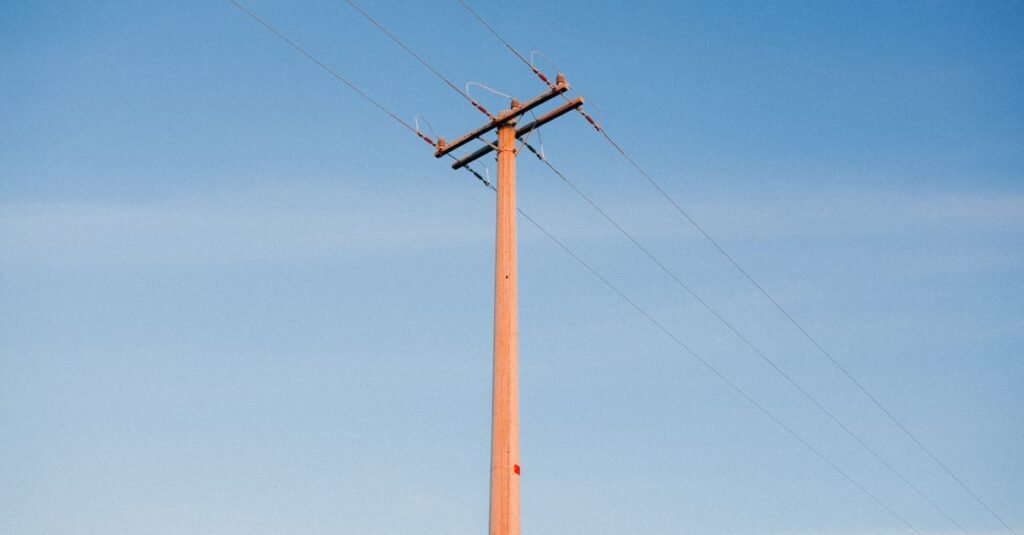 Poste de energia com cabos e cruzeta contra o céu azul