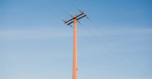 Poste de energia com cabos e cruzeta contra o céu azul