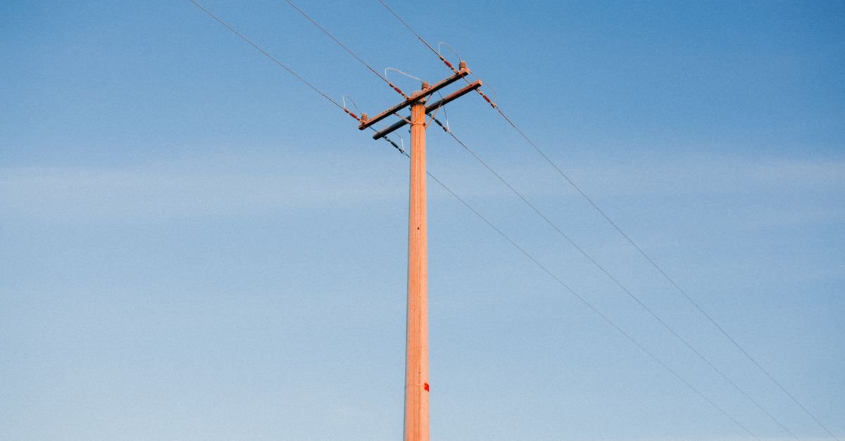 Poste de energia com cabos e cruzeta contra o céu azul