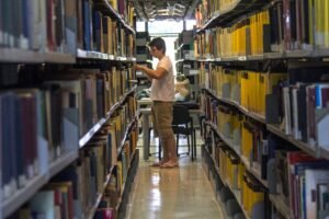 Estudante entre estantes de livros da Biblioteca Central da Universidade de Brasília